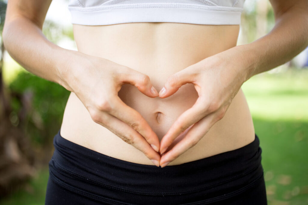 close up female hands shaping heart belly